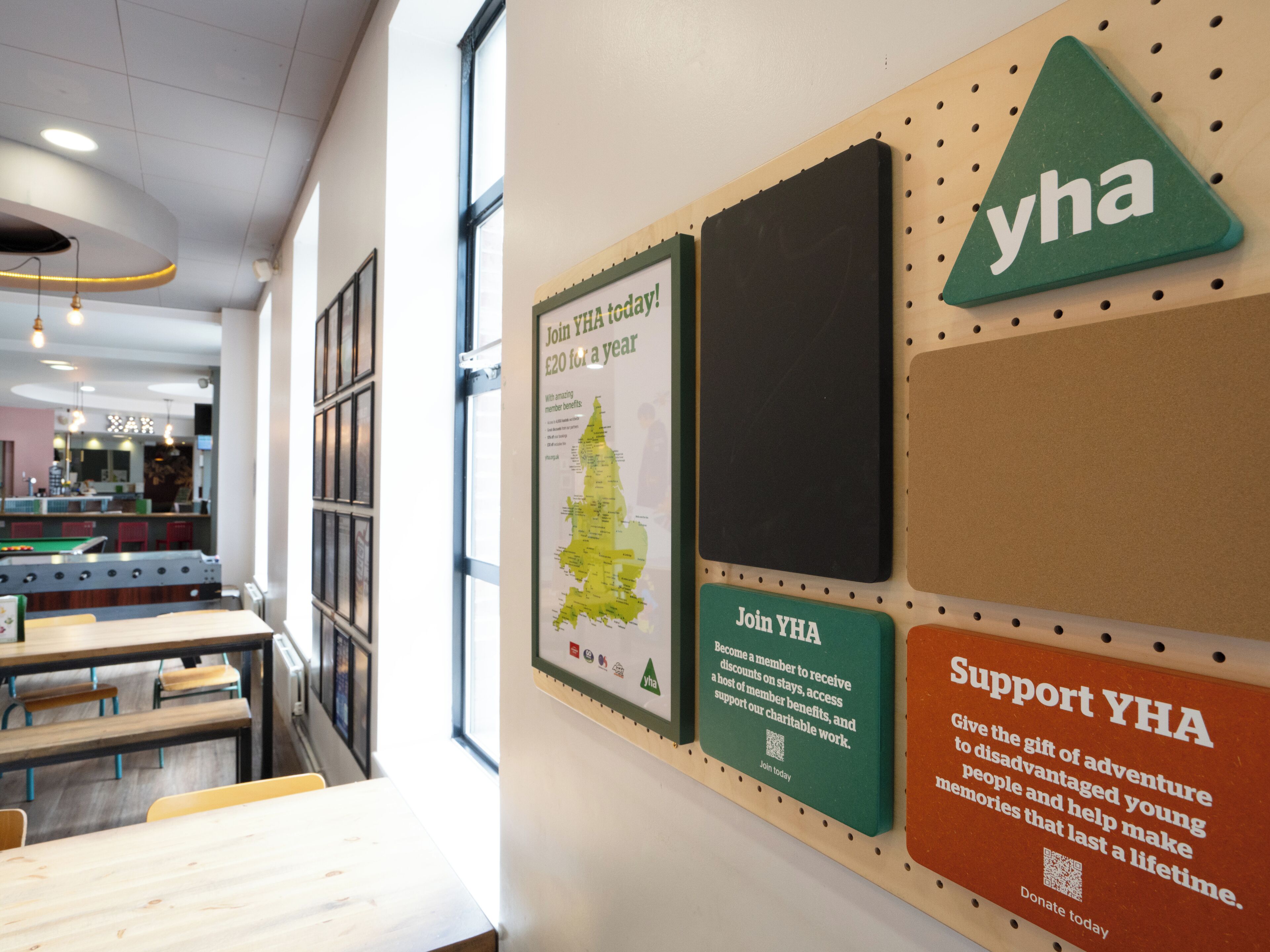 A wall with various YHA promotional materials, including a map, a membership sign, and a support sign.