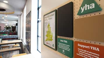 A wall with various YHA promotional materials, including a map, a membership sign, and a support sign.