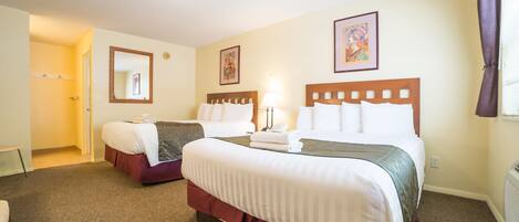 A hotel room with two beds, a sitting area, and a bathroom.