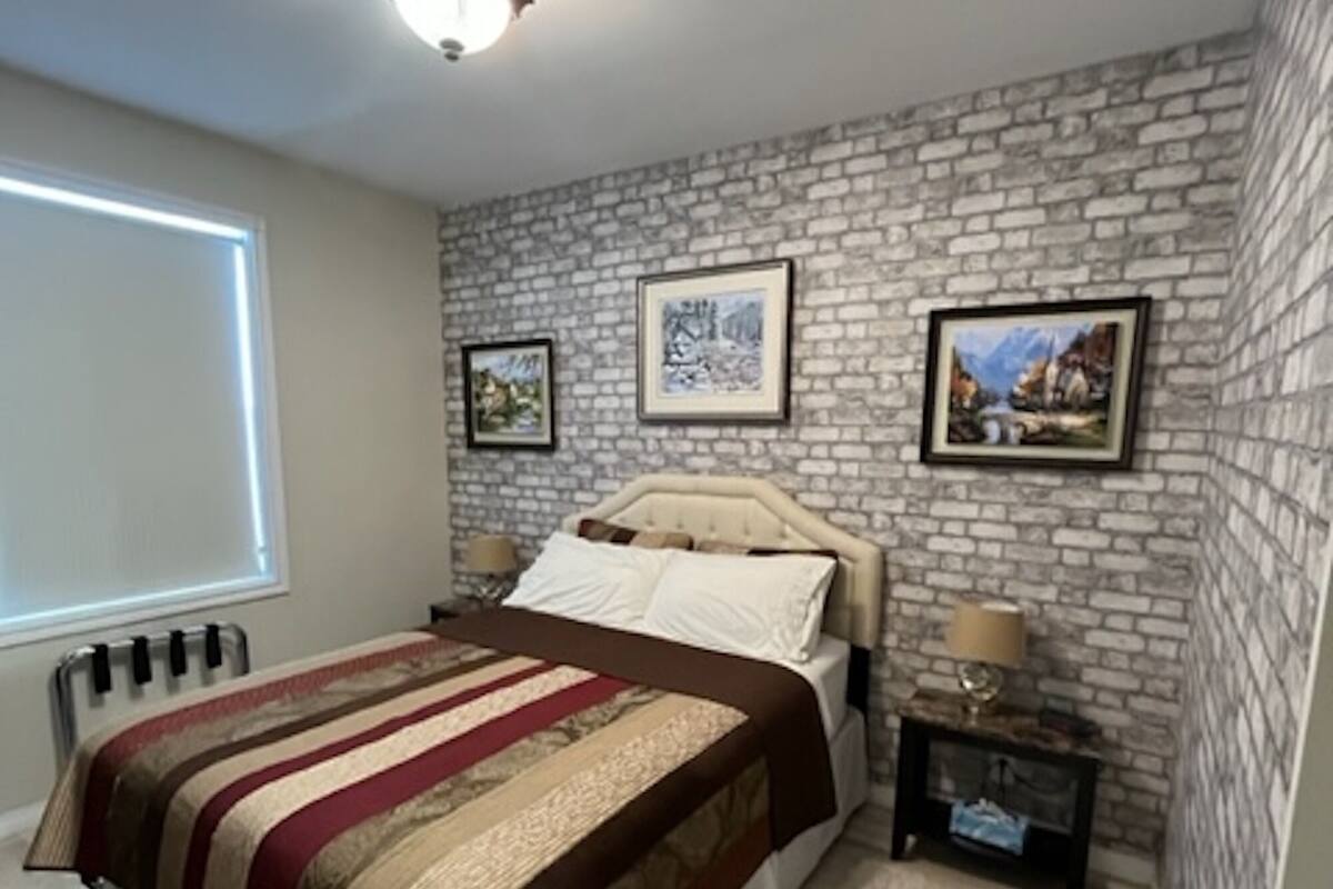 A bedroom with a bed, a nightstand, a lamp, and a window.