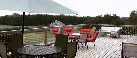 A wooden deck with outdoor furniture, including a table and chairs, and a large umbrella providing shade.