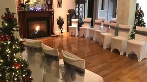 A room with a fireplace, a Christmas tree, and rows of chairs arranged for an event. - Honeycomb Bed & Breakfast (Onanole)