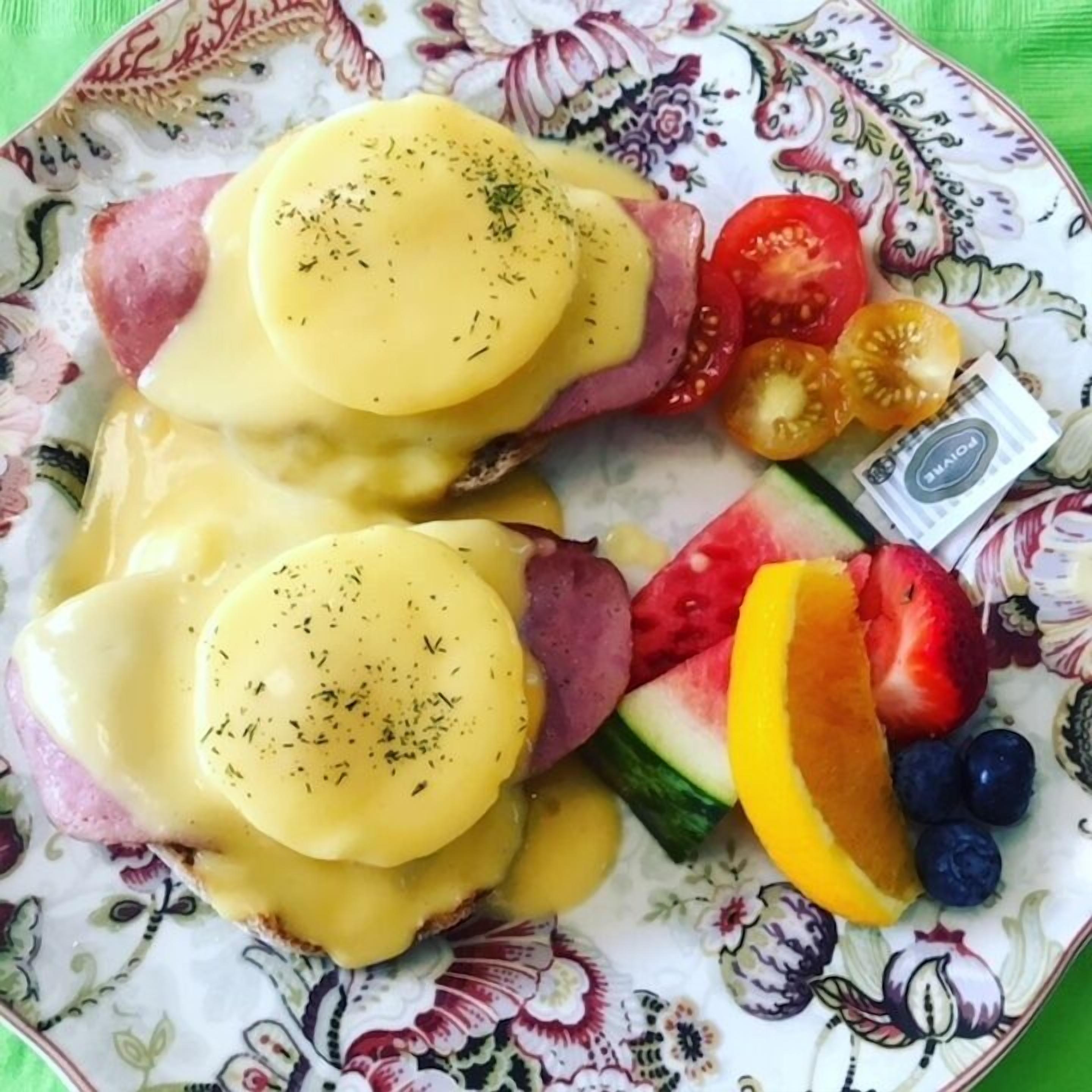 En tallrik med ägg benedict, tomater, vattenmelon och blåbär.