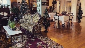 A spacious lobby with a wooden floor, a patterned rug, a sofa, and a dining area with a table and chairs. - Honeycomb Bed & Breakfast (Onanole)