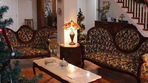 A living room with a chandelier, two patterned sofas, a coffee table, and a staircase with a garland. - Honeycomb Bed & Breakfast (Onanole)