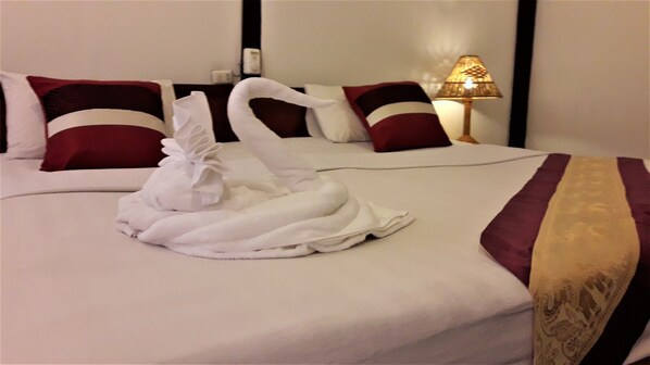 Habitación de hotel con una cama bien hecha, una lámpara y un cojín decorativo.