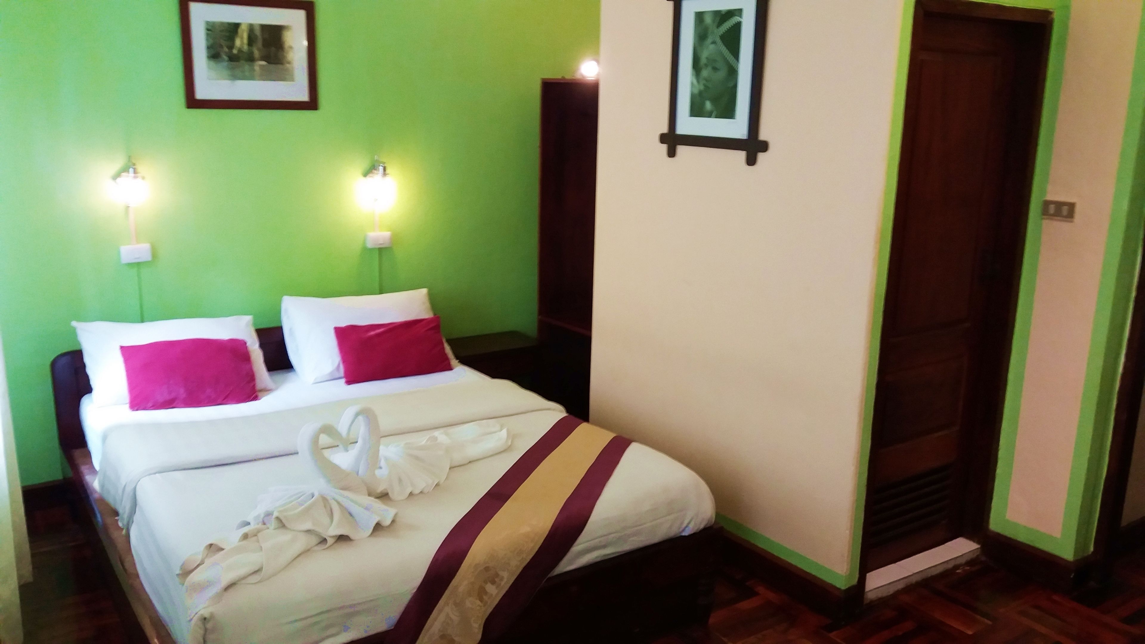 Habitación de hotel con cama, dos lámparas de noche, una foto enmarcada en la pared y una puerta.