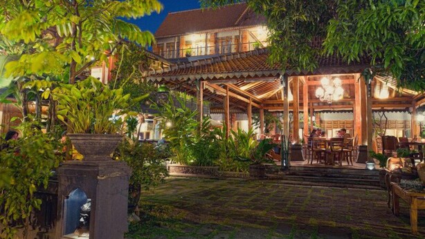 A traditional building with a covered patio area, surrounded by lush greenery. - Omah Sinten Heritage Hotel & Resto (Surakarta)