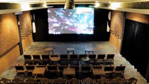 A cinema with wooden seats and a large screen at the front. - Omah Sinten Heritage Hotel & Resto (Surakarta)