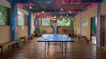 Una mesa de ping pong en una habitación con paredes de ladrillo, suelo de madera y ventanas amplias.