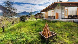 A modern lodge with stone walls and large windows, a wooden deck, and a fire pit in the foreground. - Larisa Resort, Manali (Manali)