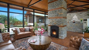 A spacious living area with leather sofas, a round coffee table, and a stone fireplace. - Larisa Resort, Manali (Manali)