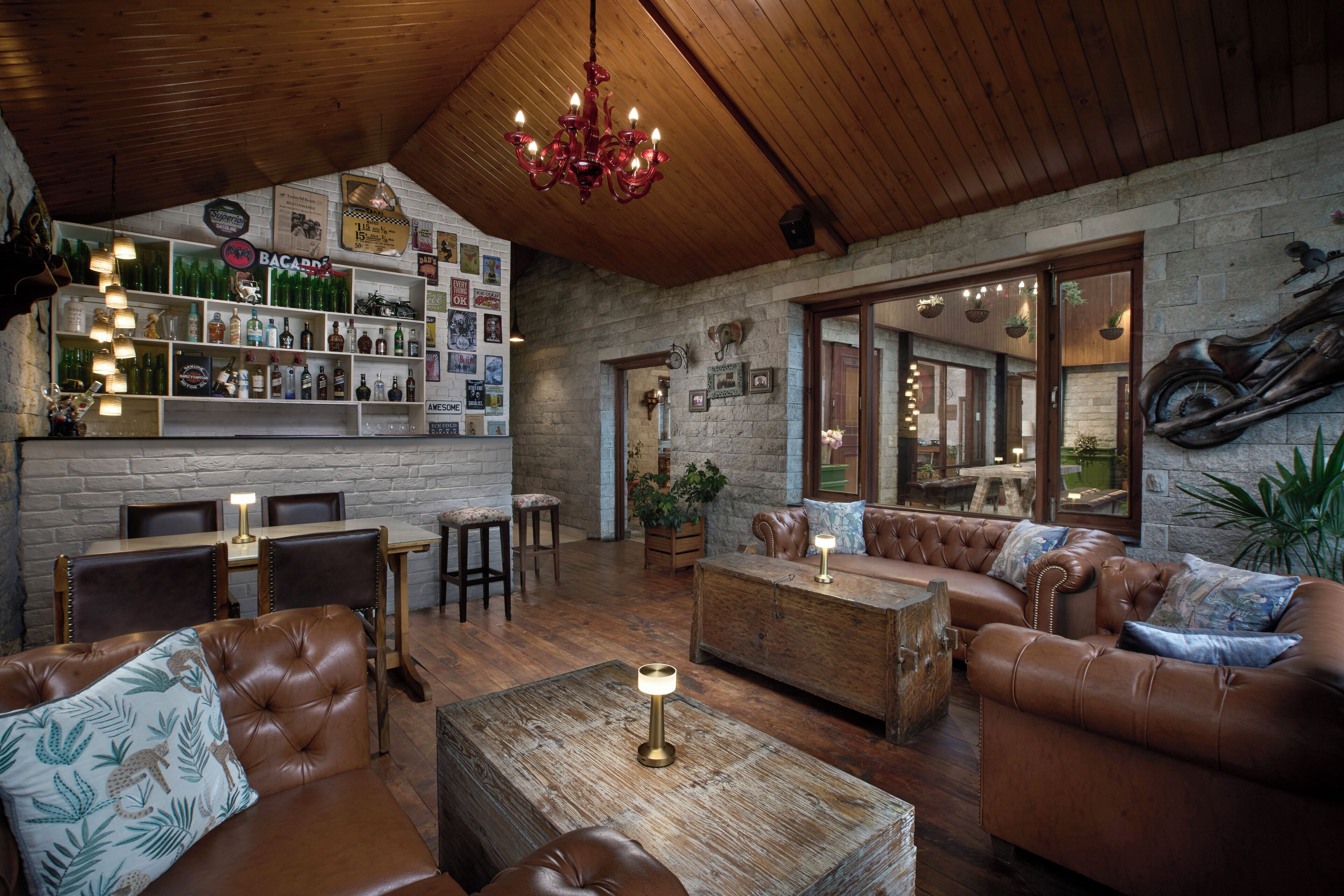 Un intérieur chaleureux avec des canapés en cuir, une table basse en bois et un coin bar agrémenté de bouteilles et de photos encadrées.