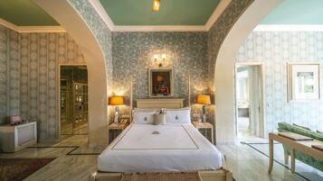 Um quarto espaçoso com uma cama grande, duas mesas de cabeceira com abajures, um criado-mudo e um sofá verde.