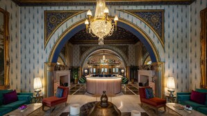 Un lobby lujoso con un bar central, candelabros ornamentales y muebles clásicos.