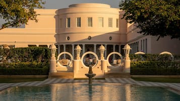 A building with a fountain in front, surrounded by a pool and greenery.