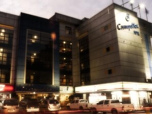 Een hotel met een moderne gevel, meerdere verdiepingen en een opvallend bord met de tekst 'Cosmetology'.