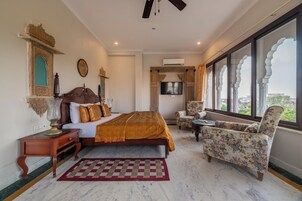 A bedroom with a bed, a chair, a TV, and a window with a view.
