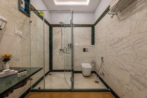 Uma casa de banho moderna com cabine de duche em vidro, sanita e chão em mosaico de mármore.