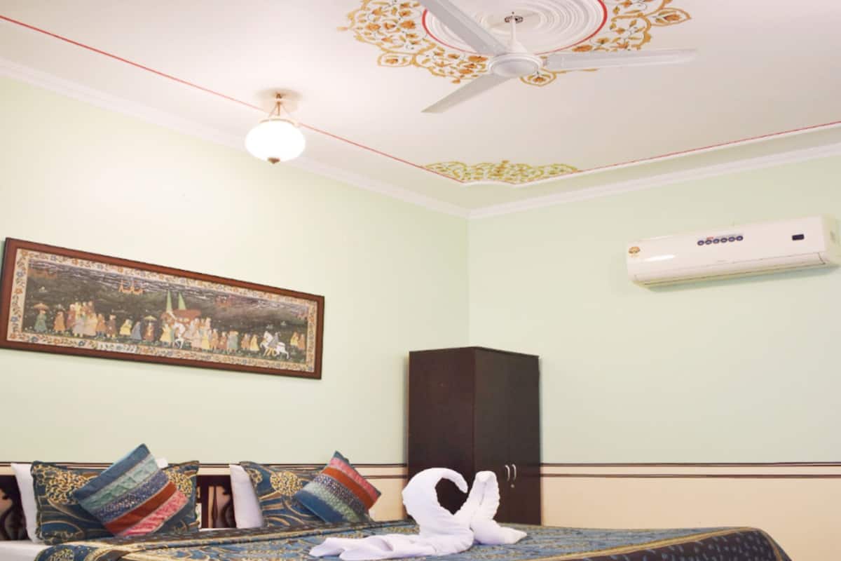 A room with a bed, a ceiling fan, a wall-mounted air conditioner, and a framed picture.