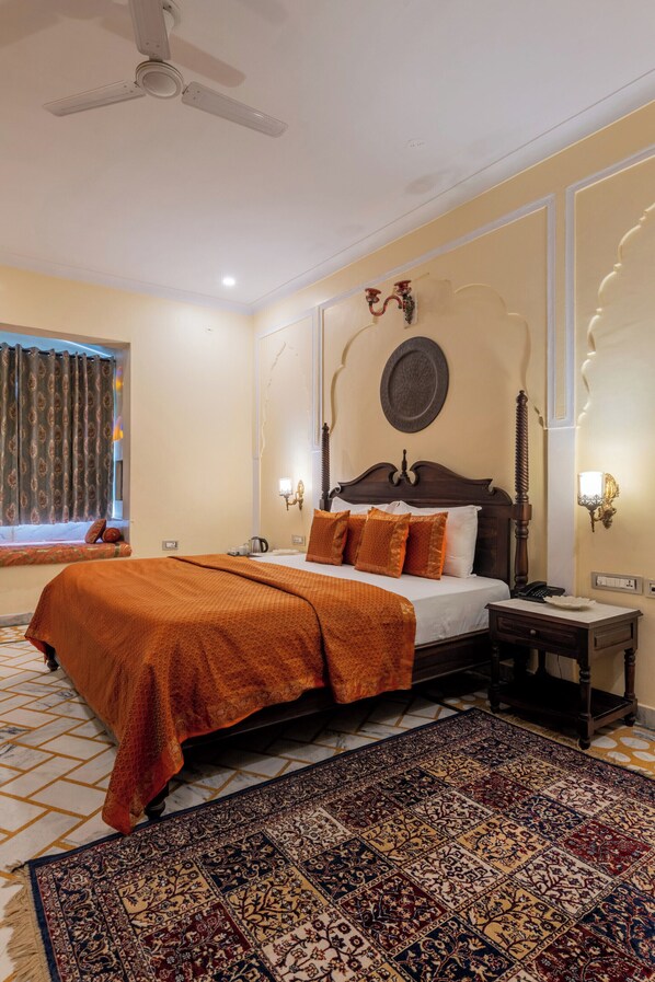 A bedroom with a bed, a nightstand, a wall-mounted lamp, a ceiling fan, and a patterned rug.