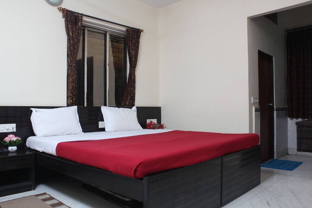 A modern bedroom with a black bed, white bedding, and a red throw.