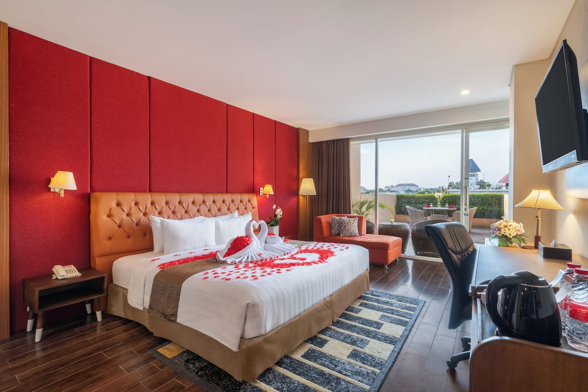 Une chambre d’hôtel avec un grand lit, un bureau, une chaise, une télévision et une vue sur la ville.
