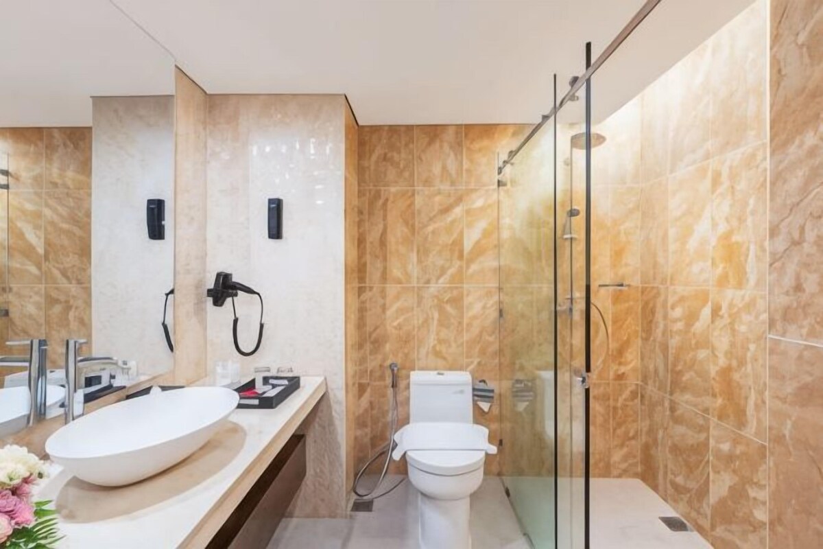 A modern bathroom with a large sink, toilet, and glass shower enclosure.