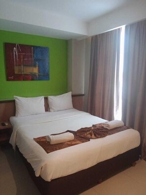 Une chambre d’hôtel avec un grand lit, une table de chevet, un tableau au mur et une fenêtre avec des rideaux.