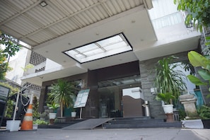 A building entrance with a ramp, potted plants, and a signboard.