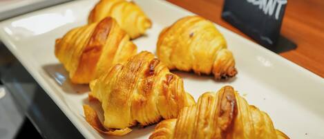 A plate of croissants on a table with a sign labeled 'Croissant' in the background.