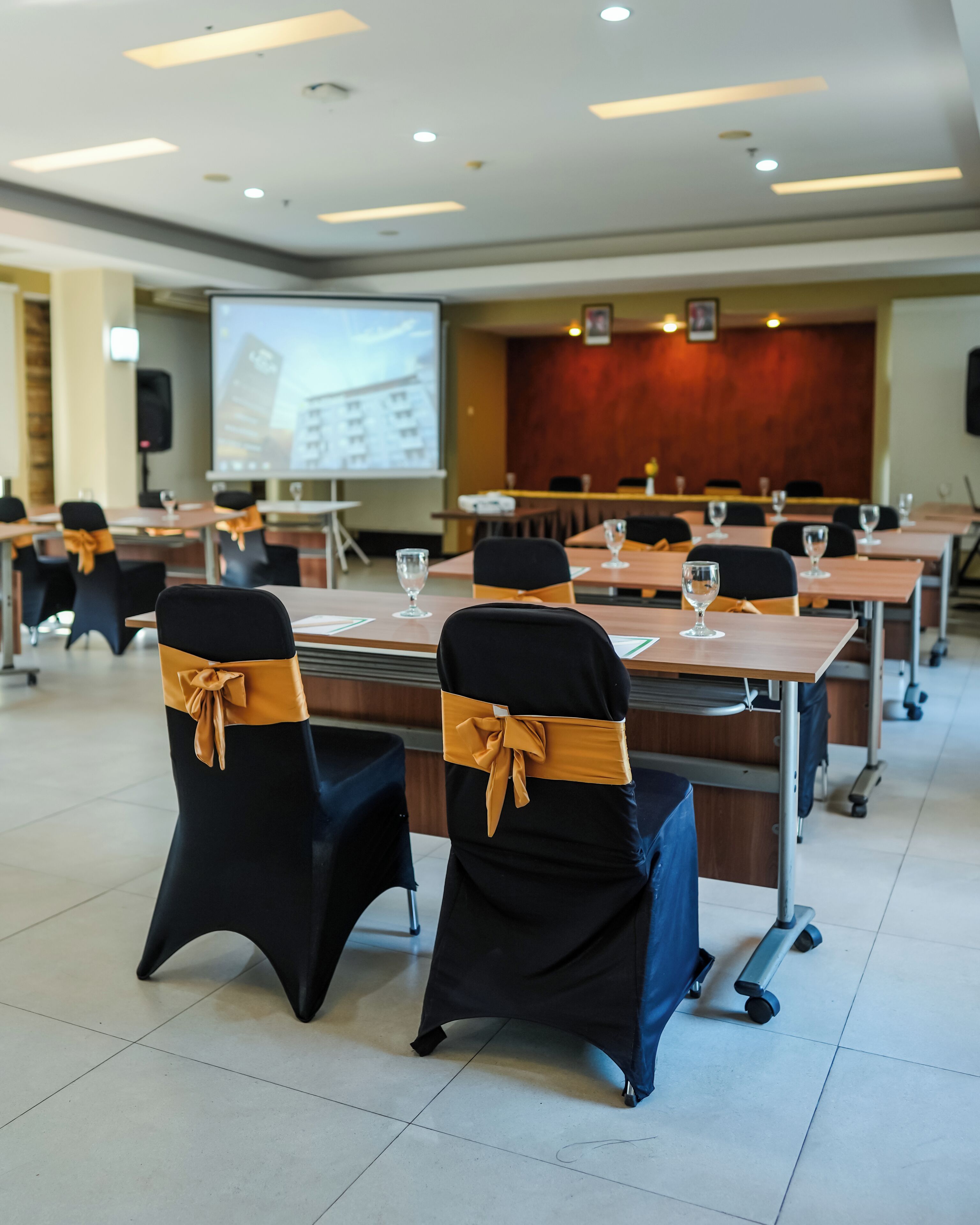 Une salle de conférence équipée de tables, de chaises et d’un écran de présentation.