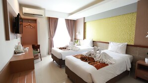 Une chambre d’hôtel avec deux lits, un bureau, une chaise, une télévision et un appareil de climatisation.