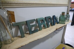 A shelf with the word "TERRA" spelled out in large letters, a glass bottle, and two small glass bottles with cork stoppers. - Terra Guesthouse 2 (Busan)
