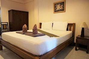 A neatly made bed with white linens, a wooden headboard, and a small bedside table with a lamp. - My Mum Home (Chiang Mai)