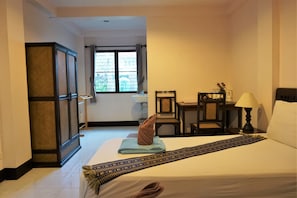 A hotel room with a bed, a desk, a chair, a lamp, and a window. - My Mum Home (Chiang Mai)