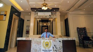 Un mostrador de recepción con una araña, encimera de mármol y un letrero que dice "The Raj Vilas Boutique Hotel".