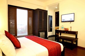 Habitación de hotel con una cama grande, televisión, escritorio y vistas al exterior.