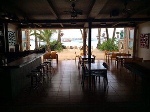 An indoor dining area with a view of a beach and ocean. There are multiple tables and chairs arranged for dining. - The Rose Pike at Boracay (Boracay Island)