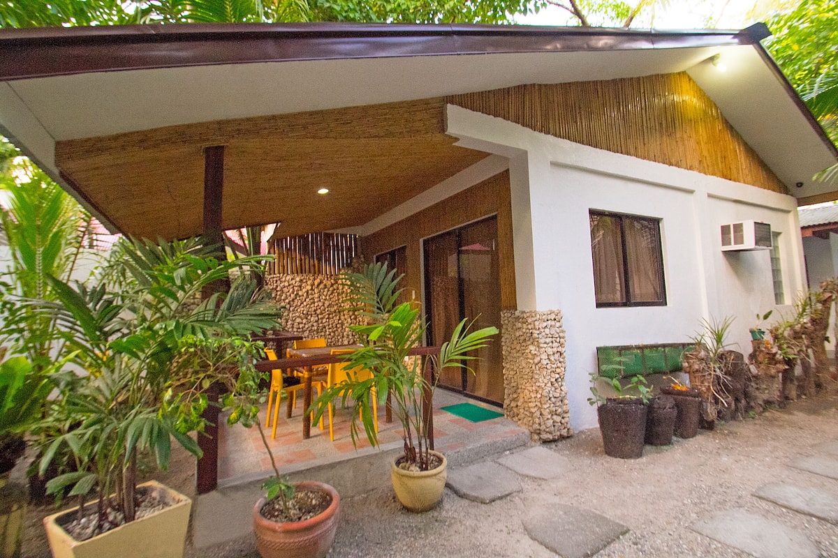 A modern house with a covered patio, potted plants, and a dining area.