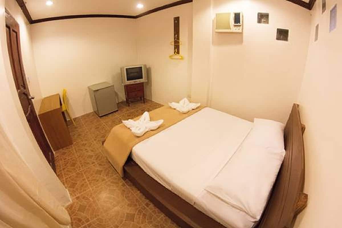 A hotel room with a bed, a television, and a small cabinet.