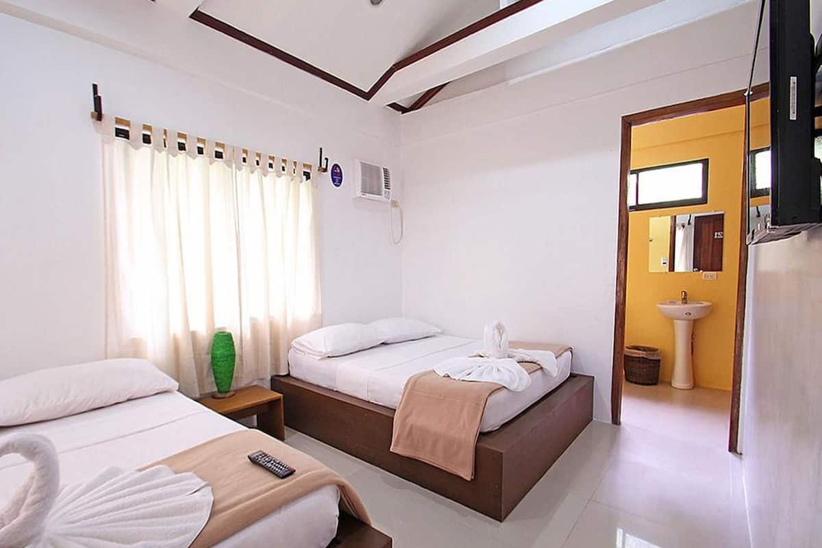 A hotel room with two beds, a bathroom with a sink, and a television.