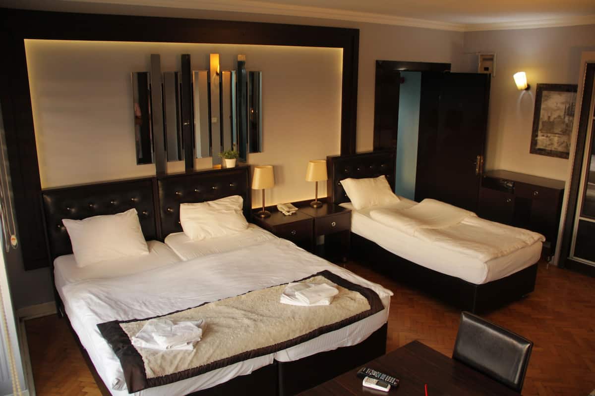 A hotel room with two beds, a large mirror, bedside tables with lamps, a desk, and a chair.