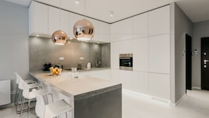 A modern kitchen with a central island, stainless steel appliances, and pendant lighting. - Exclusive Apartments | Krakow Lubicz Brewery (Kraków)