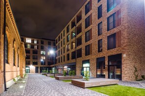 A courtyard with brick buildings, a paved walkway, and small planters. - Exclusive Apartments | Krakow Lubicz Brewery (Kraków)