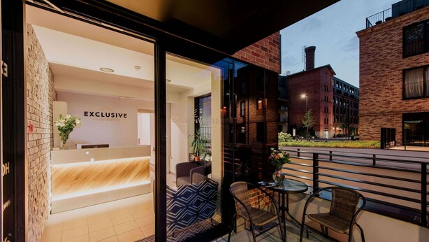 A modern hotel entrance with a reception desk, seating area, and a view of the street. - Exclusive Apartments | Krakow Lubicz Brewery (Kraków)
