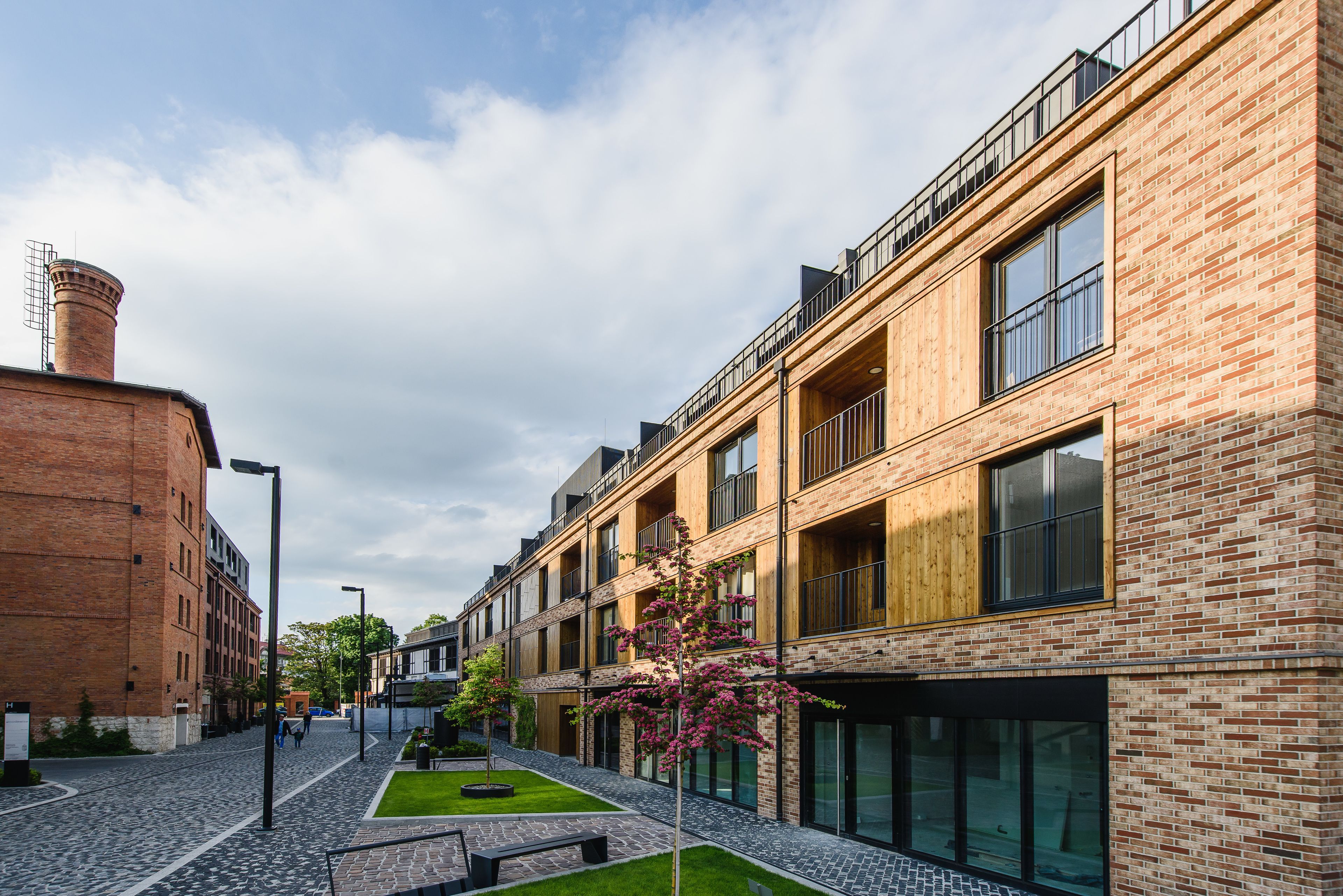 A modern building with brick facade, large windows, and a courtyard with a tree.