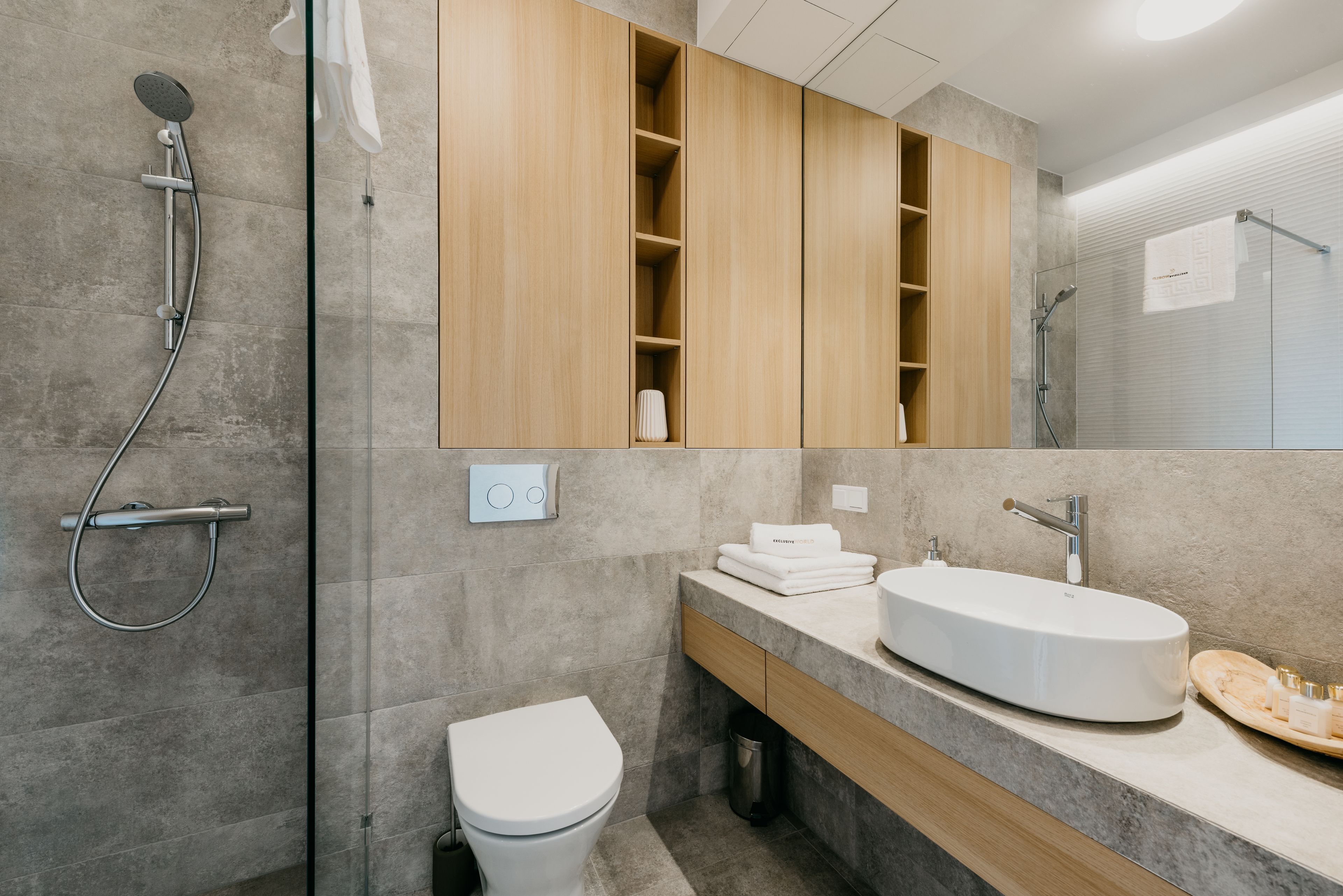 A modern bathroom with a shower, toilet, vanity, and a large mirror.