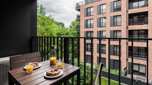 A balcony with breakfast items, a bottle of orange juice, and a glass of orange juice. - Exclusive Apartments | Krakow Lubicz Brewery (Kraków)