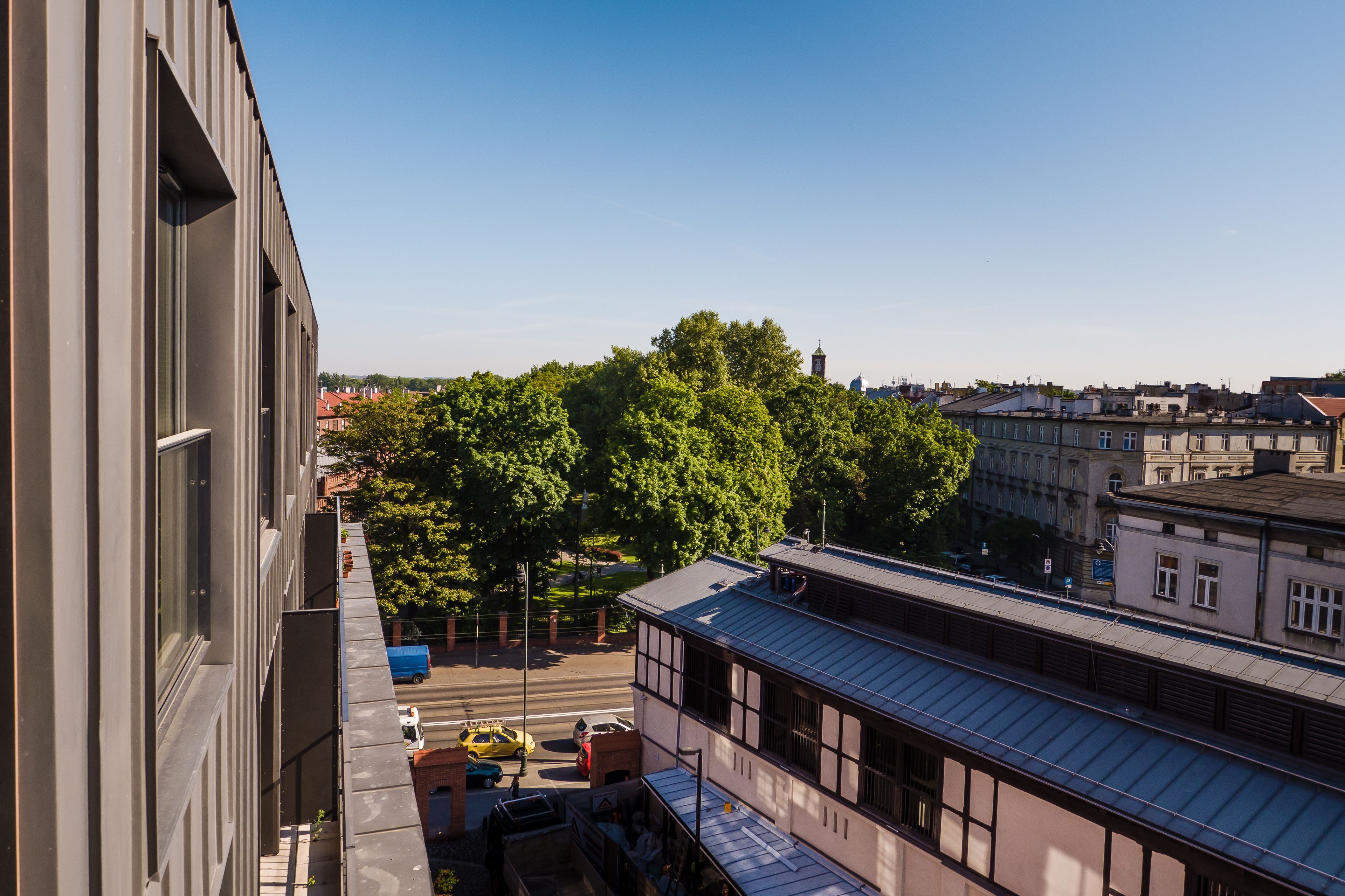 A high-rise building with a view of a tree-lined street below.